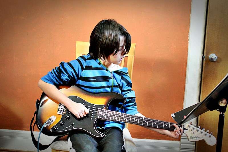 A student, Aidain, playing the guitar.