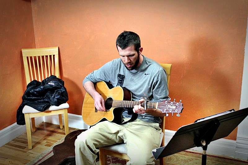A student, Bobby, playing the guitar.